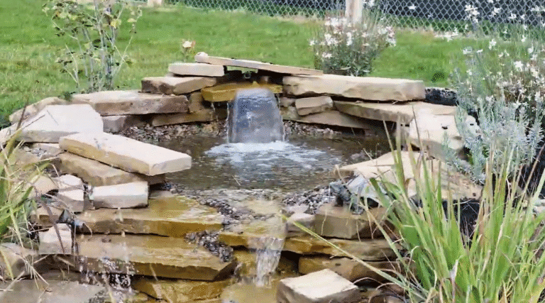 Tranquil garden water fountain surrounded by rocks and lush greenery, creating a peaceful outdoor space for relaxation and reflection.